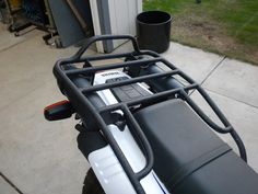 the front end of a motorcycle parked in a driveway next to a building with a trash can