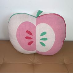 an apple pillow sitting on top of a brown couch