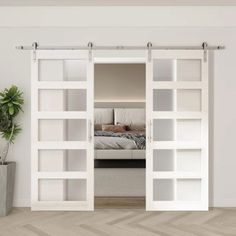 an open sliding door in a bedroom with a bed and potted plant next to it