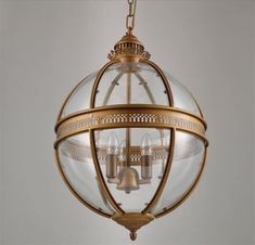 an antique brass finish hanging light fixture with glass globes and filigreens