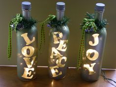 three wine bottles decorated with gold letters and green ribbon tied around the top, sitting on a table