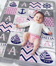 a baby laying on top of a blanket next to an anchor and sailboat pattern