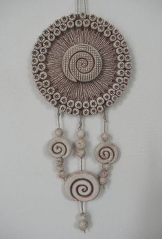 a decorative wall hanging with beads and spirals in the center on a white wall