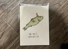 a card with a drawing of a fish wearing a birthday hat on it's head