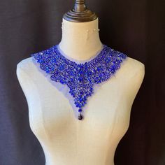 a white mannequin with a blue necklace on it's neck and bottom