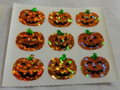 orange sequinized pumpkins on white paper with green leaves and glitter eyes for halloween decorations