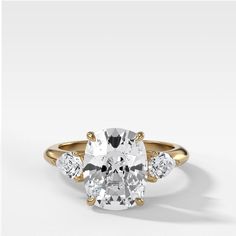 an oval diamond ring with three pear shaped diamonds on the band and side stones in yellow gold