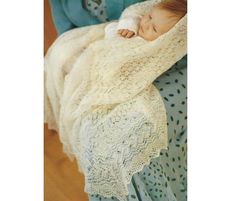 a baby wrapped in a white blanket is laying on a blue chair with polka dots