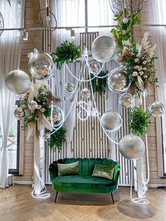 a green couch sitting in front of a mirror ball wall hanging from it's ceiling