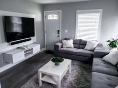 a living room with grey couches and white coffee table in front of a flat screen tv