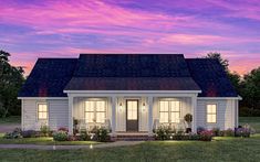 a small white house is lit up at night with the sun setting in the background