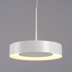 a white circular light fixture hanging from a ceiling in a room with grey walls and flooring