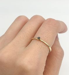 a woman's hand wearing a gold ring with a black diamond