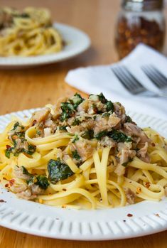 a white plate topped with pasta and meat covered in sauce on top of a wooden table