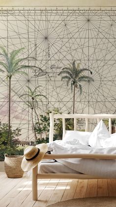 a white bed sitting on top of a wooden floor next to a wall with palm trees