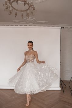 a woman standing in front of a white backdrop wearing a dress made out of feathers