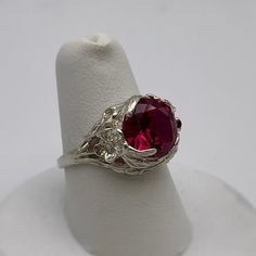 Gorgeous Floral Ruby Ring in Sterling Silver  * 4ct Ruby measures 10mm Round  * Solid Sterling Silver  * Size 7 - sizing available  Also available in 10k, 14k and 18k Gold - message me for current Gold pricing.    Hallmarked and Gift Ready!  This 4ct Ruby is Laboratory Grown. It is identical to natural in every way, including Chemistry, Composition & Hardness with flawless clarity & excellent color refraction.  TIMELESS, BEAUTIFUL & UNIQUE FINE ART JEWELRY! Formal Ruby Gemstone Ring, Formal White Gold Crystal Ring With Round Stone, White Gold Ruby Jewelry, Silver Rings With Lab-created Ruby, Formal Silver Crystal Ring With Birthstone, Formal Cubic Zirconia Ruby Ring, Silver Jewelry With Lab-created Ruby Center Stone, Formal White Gold Ruby Ring With Round Stone, Round Cut Ruby Jewelry With Center Stone