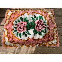 a pink rug with flowers on it sitting on top of a wooden floor next to a wall