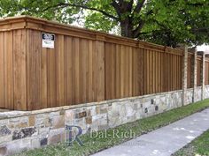 a wooden fence next to a sidewalk and trees