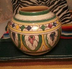 a decorative vase sitting on top of a colorful rug next to a zebra print pillow