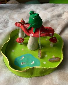 a frog sitting on top of a green tray with mushrooms and other things in it