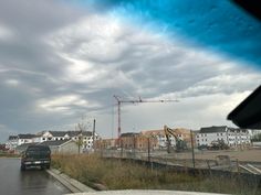 a truck driving down a street next to tall buildings under a cloudy sky with construction cranes in the background