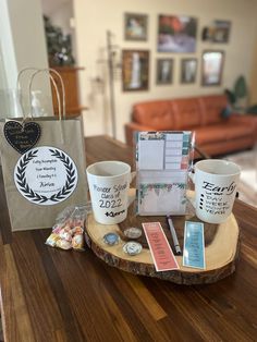 two coffee mugs sitting on top of a wooden table next to a paper bag