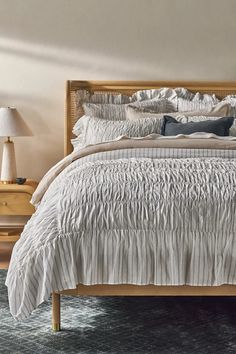 the bed is made with white ruffled sheets and pillows on top of it, along with two nightstands