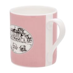 a pink and white coffee mug with an image of a town on it's side