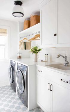 a washer and dryer in a white laundry room with patterned floor tiles on the floor