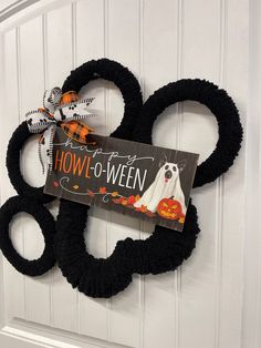 a door hanger decorated with black yarn and a sign that says how - to - ween