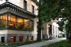 a large building with lots of windows and plants on the side walk next to it