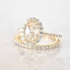 an engagement ring with a pear shaped diamond surrounded by smaller round brilliant cut diamonds in yellow gold