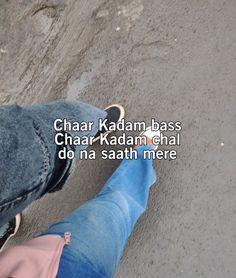 the feet of a person wearing blue jeans and black shoes with words written on them