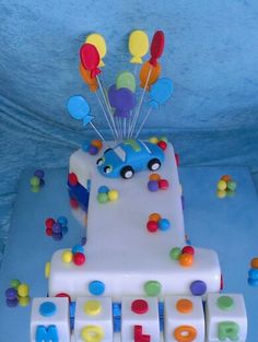 a birthday cake decorated with balloons and letters