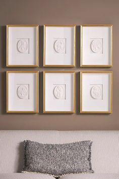 four framed pictures hang on the wall above a couch with a pillow and throw pillow