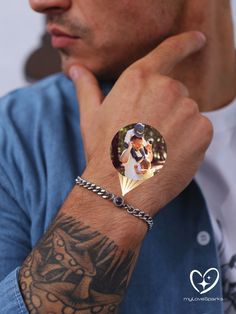 a man with a tattoo on his arm wearing a ring and bracelet that has a diamond in it