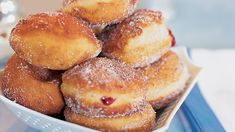 a bowl filled with sugar covered donuts on top of a blue and white table