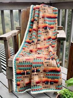 a blanket sitting on top of a wooden bench next to a potted green plant