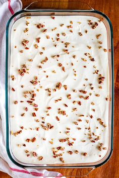 a casserole dish filled with white frosting and chopped pecans