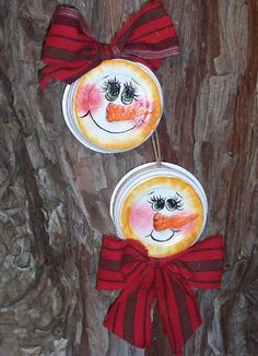 two paper plates with faces painted on them are hanging from a tree in the woods