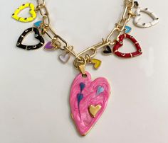 This one-of-a-kind heart necklace is colorful and whimsical. Five colorful hearts and eight mini hearts dangle from a gold tone paperclip link chain. The center large pink heart measures 1 x 1 3/4". Four more hearts measure approx 3/4" x 3/4". Necklace measures 17" with a 1" extender. Pink Heart-shaped Jewelry With Dangling Charms, Pink Heart Pendant Charm Necklace With Lobster Clasp, Pink Heart-shaped Charm Necklaces With Lobster Clasp, Pink Heart-shaped Charm Necklace With Lobster Clasp, Playful Pink Jewelry With Adjustable Chain, Pink Heart Charm Necklaces For Jewelry Making, Dangle Heart Charm Necklace, Pink Dangle Charm Necklace With Adjustable Chain, Multicolor Dangle Jewelry For Valentine's Day