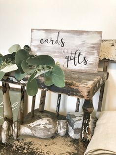 a wooden sign that says cards gifts sitting on top of a bench next to some rocks