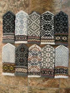 knitted mittens laid out on a stone wall in different colors and patterns, all lined up together