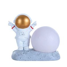 a white and gold astronaut figurine next to an egg on top of a rock