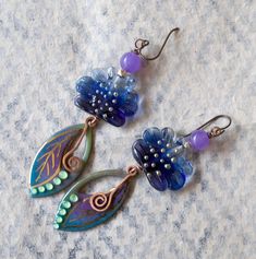 Jewel toned earrings featuring green, blue and purple leaf shaped enameled charms with gold details. They are topped with ruffled blue lampwork beads, sterling beads and purple quartz beads. Simple copper swirls dangle from the center. These stylish earrings measure 3 3/8 inches in total length and hang on niobium earring hooks. Return to shop: bstrung.etsy.com More links where you can find me: Facebook: http://www.facebook.com/bstrung Pinterest: http://pinterest.com/bstrung Instagram: https://w Artsy Purple Drop Earrings, Whimsical Blue Nickel-free Earrings, Handmade Blue Whimsical Flower Earrings, Whimsical Handmade Blue Flower Earrings, Artistic Purple Jewelry With Matching Earrings, Nickel-free Purple Enamel Jewelry, Unique Hand Painted Purple Earrings, Artistic Nickel-free Purple Jewelry, Whimsical Hand Painted Blue Earrings