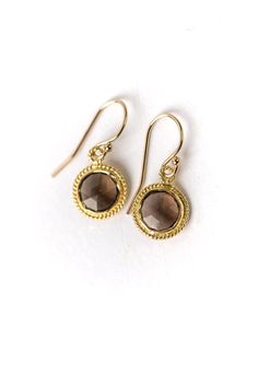 Smoky quartz is known for its grounding effect, which is emphasized by the balanced circular shape in this artisan design. The bezel, set in gold, is uniquely detailed with matching gold filled ear wires. Smoky quartz is a beautiful neutral addition to your jewelry collection that is an AVD Favorite! Gold Filled (Lead & Nickel Free) Smoky Quartz 1", with gold filled ear wires We hand select our natural materials, thus there may be slight variations in color and/or size that will not detract Faceted Round Brass Jewelry, Round Brass Jewelry With Bezel Setting, Gold Round Earrings With Bezel Setting, Elegant Gold Jewelry With Smoky Quartz, Smoky Quartz Yellow Gold Jewelry Gift, Yellow Gold Smoky Quartz Jewelry Gift, Elegant Yellow Gold Smoky Quartz Jewelry, Gold Smoky Quartz Gemstone Jewelry, Bezel Earrings