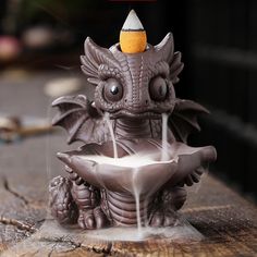 a dragon fountain is sitting on top of a piece of wood and it's spewing out water