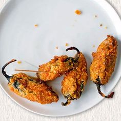 three chicken skewers on a white plate with mustard sprinkled over them