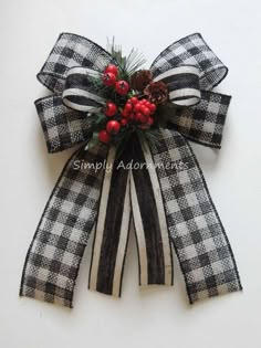 a black and white checkered bow with berries, pine cones and holly on it